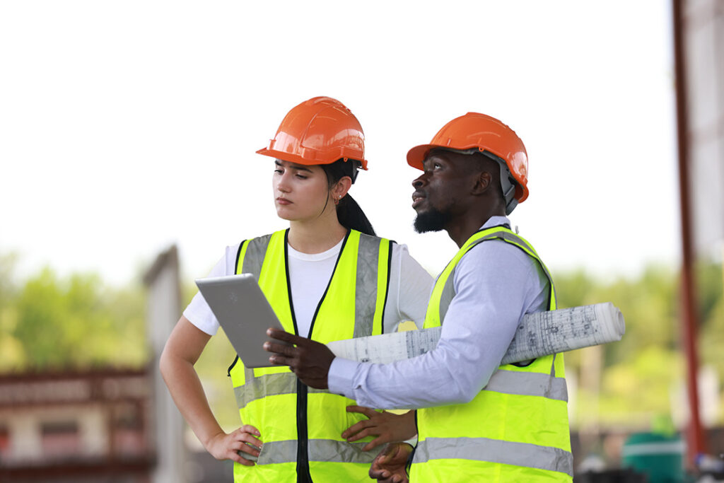 Architects working together wearing safety helmets and vests.
